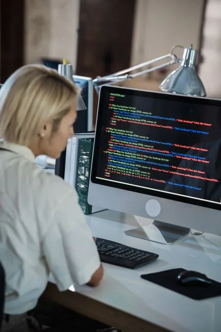 Rear view of an anonymous cropped male freelancer seated at a table, working on a project on a laptop in a bright room during the day